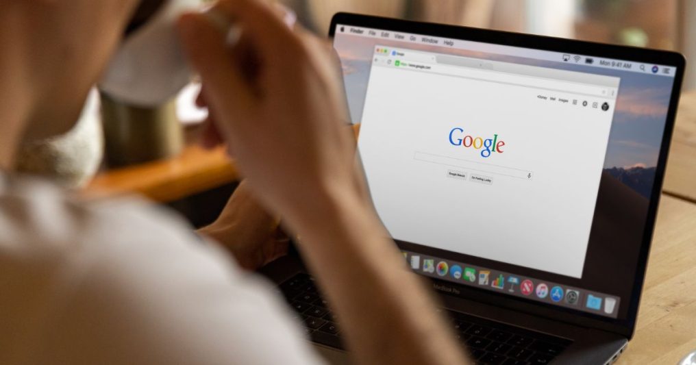 A person sips coffee while viewing the Google homepage on a laptop—symbolizing a customer searching for your business on Google and viewing your Google Business Profile.