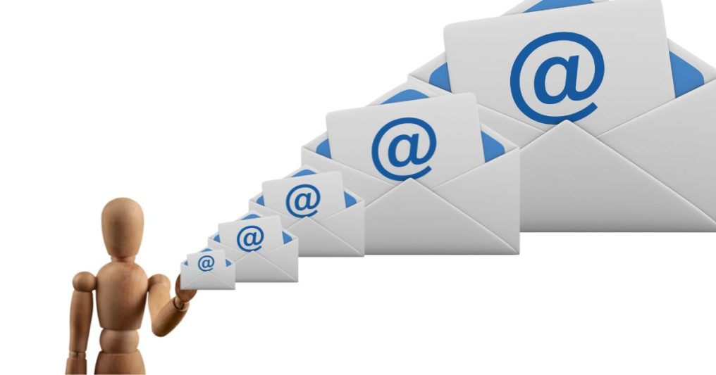 A wooden mannequin hand releases a scaling trail of email envelopes that grow larger, symbolizing how small, repeatable marketing moments build up into a big brand impact.